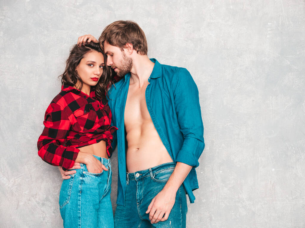 Hot beautiful woman and her handsome boyfriend. Models posing near gray wall in jeans clothes. Young passionate couple hugging before having sex. Sensual pair getting closer for kiss. Lover couple - Photo, Image