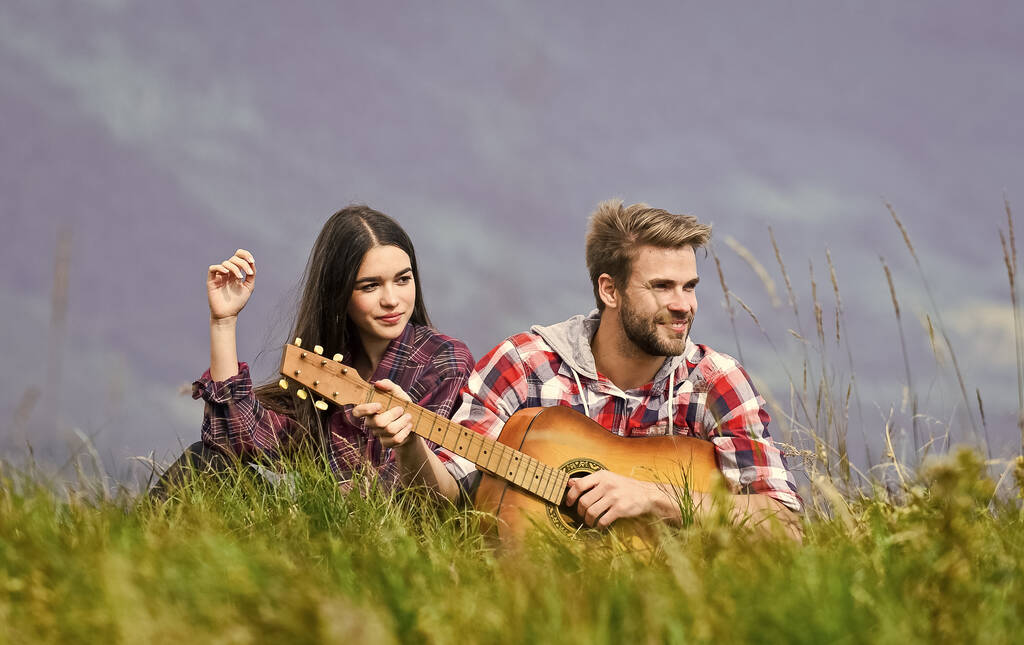 Romantyczny nastrój. Para zakochanych ciesząca się widokiem ze szczytu góry. Chłopak gra na gitarze. Śpiewa dla niej. Romantyczna wędrówka. Romantyczna para na wakacjach. Idylliczne miejsce na romantyczną randkę - Zdjęcie, obraz
