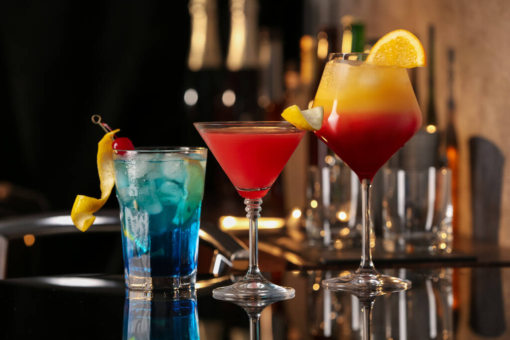 Різні смачні коктейлі на чорному столі в барі
 - Фото, зображення