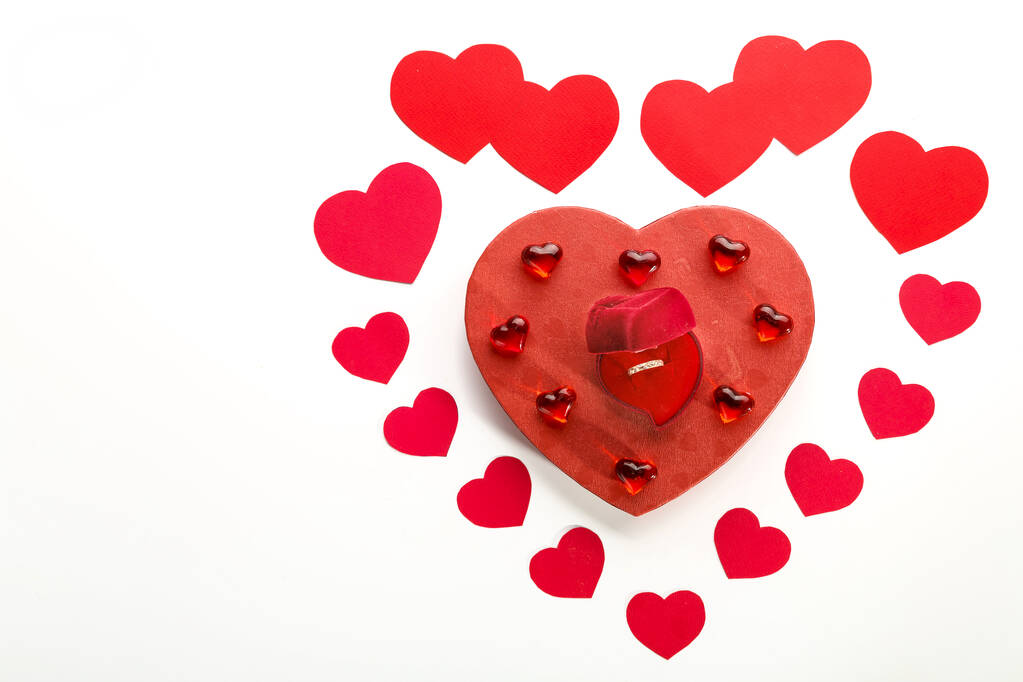 Kâğıt kalplerden yapılmış kalp, karton bir kalbin, cam kalplerin ve yüzüklü bir kutunun ortasında beyaz bir zemine serilmiş.. - Fotoğraf, Görsel