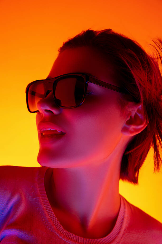 Valkoihoiset naiset muotokuva eristetty oranssi studio taustalla monivärinen neon valo - Valokuva, kuva