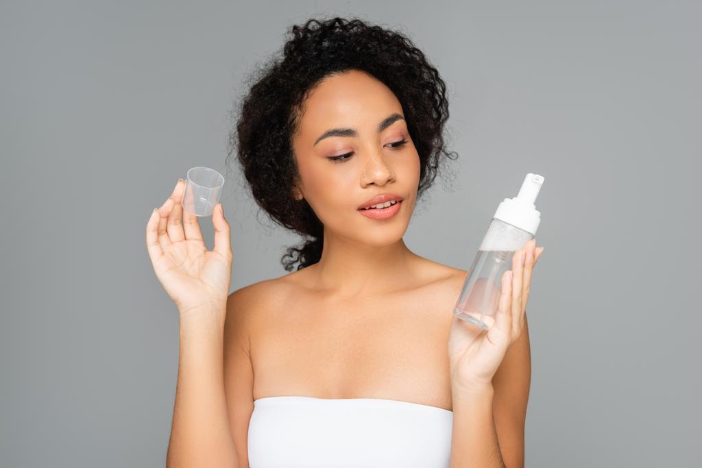 African american woman looking at cleansing foam isolated on grey  - Photo, Image
