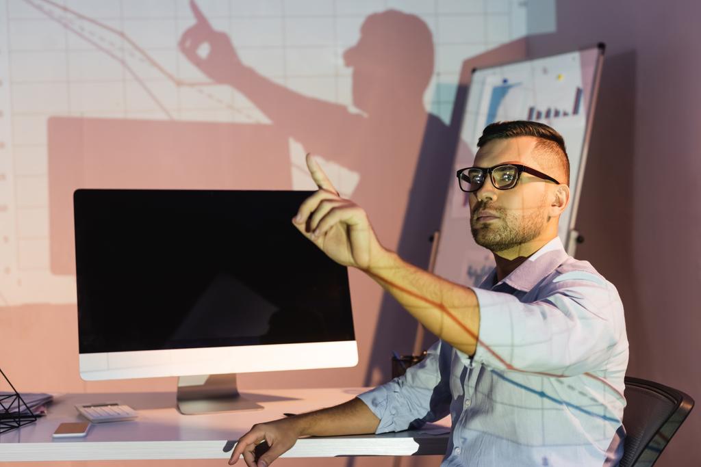 uomo d'affari in occhiali che punta con dito vicino al monitor del computer con schermo vuoto - Foto, immagini