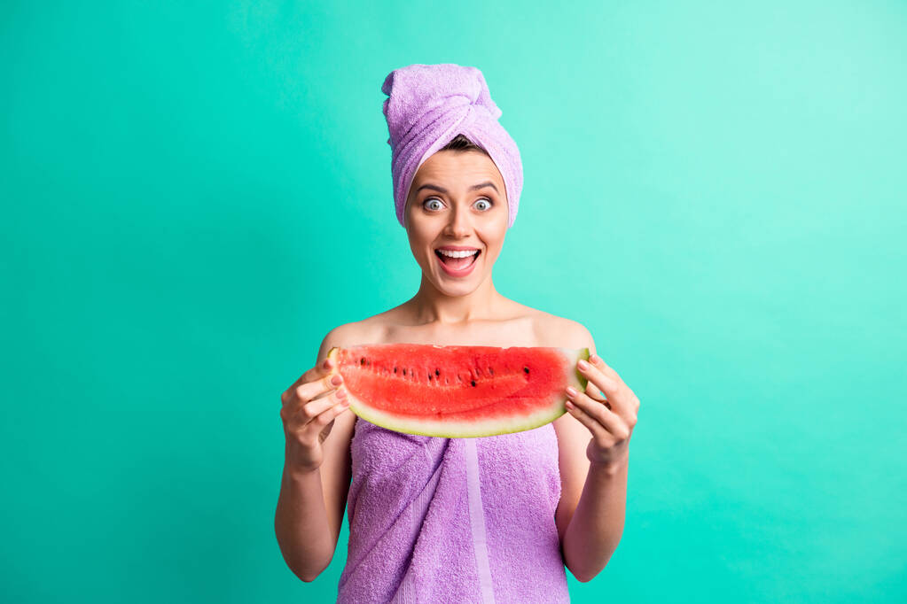Foto van mooie verbaasd dame houden grote water meloen plak lekker ontbijt dragen violette handdoeken geïsoleerde teal kleur achtergrond - Foto, afbeelding