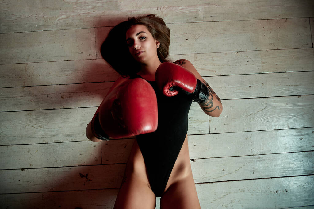 Gyönyörű nő, piros bokszkesztyűvel a tornaterem padlóján. Erő és motiváció. Boksz és fitness stílus. - Fotó, kép