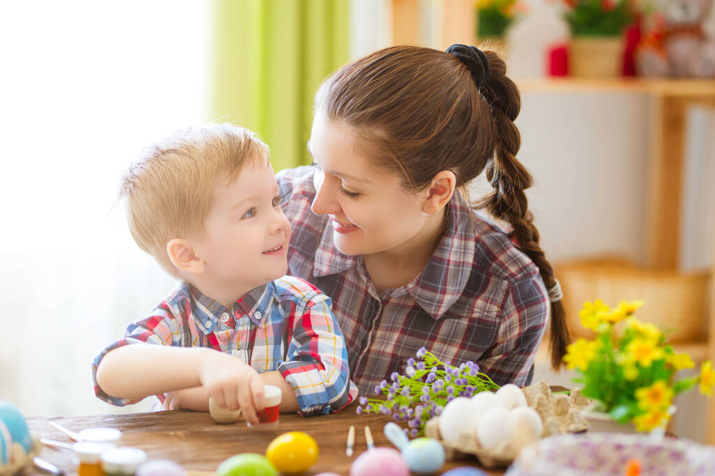 Äiti ja hänen poikansa maalaavat pääsiäismunia. Onnellinen perhe valmistautuu pääsiäispäivään. - Valokuva, kuva