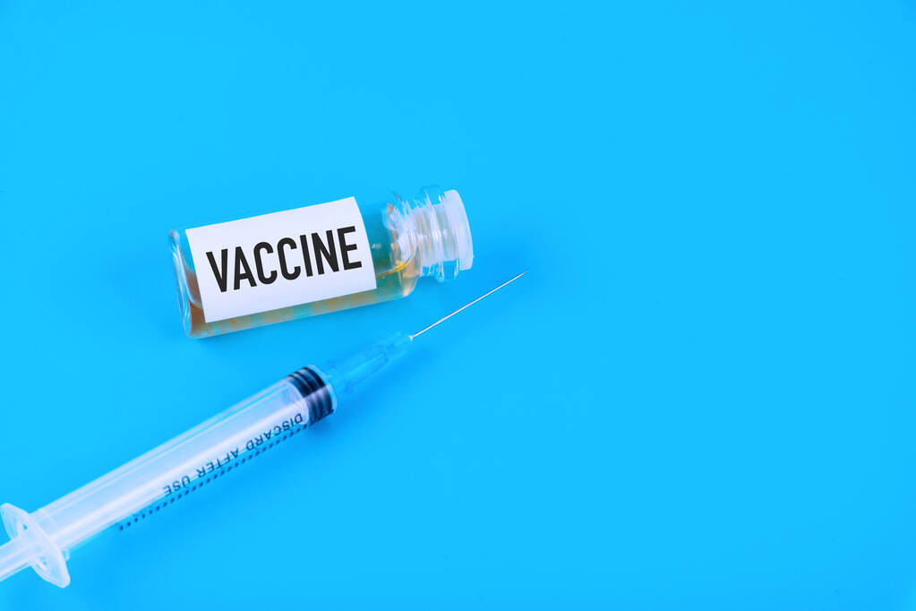 中国、武漢からのコロナウイルスの新しい発生のためのワクチンの概念。パンデミックコロナウイルスに対する予防接種。青い背景の上に. - 写真・画像