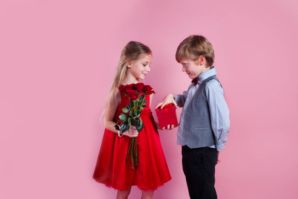 Valentijnsdag verrassing. kleine jongen in de liefde geven schattig meisje rode roos, eerste liefde - Foto, afbeelding
