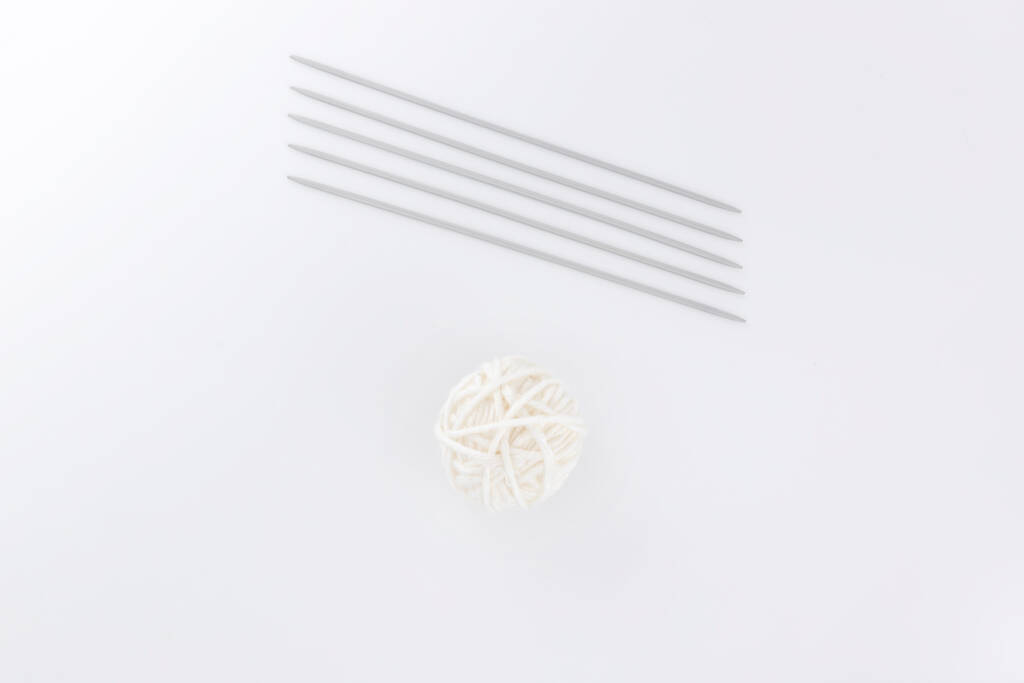 Πέντε βελόνες διπλές για πλέξιμο στο στρογγυλό και μικρό λευκό νήμα μπάλας - Φωτογραφία, εικόνα