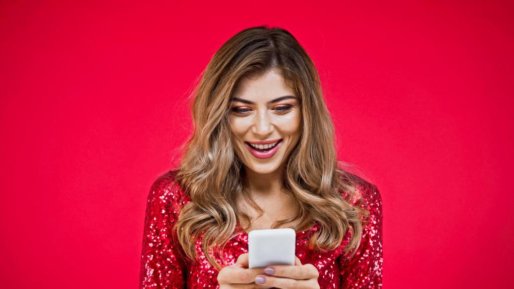 здивована жінка з хвилястим шрифтом на смартфоні ізольована на червоному
 - Фото, зображення