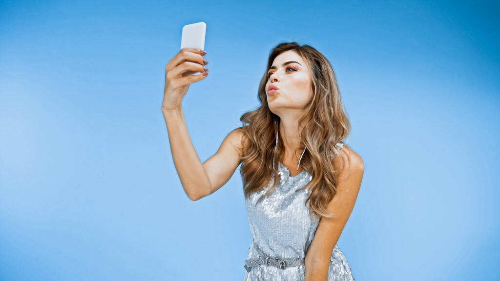 femme souffle baiser tout en prenant selfie sur bleu - Photo, image