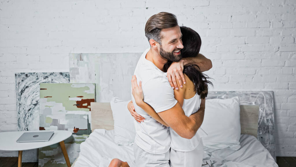 gelukkig baard man knuffelen vriendin in slaapkamer - Foto, afbeelding