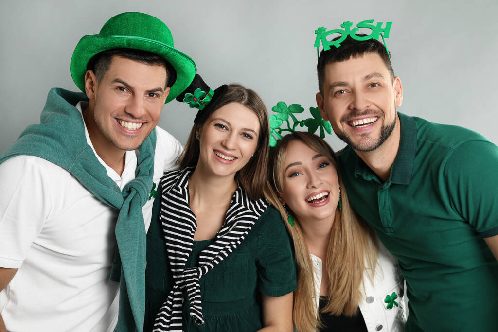Happy people in St Patrick 's Day outfits on light grey background - Фото, изображение