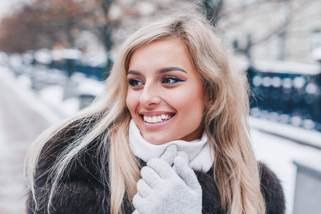 Jeune belle fille souriante portant manteau d'hiver en fourrure regardant loin - Photo, image