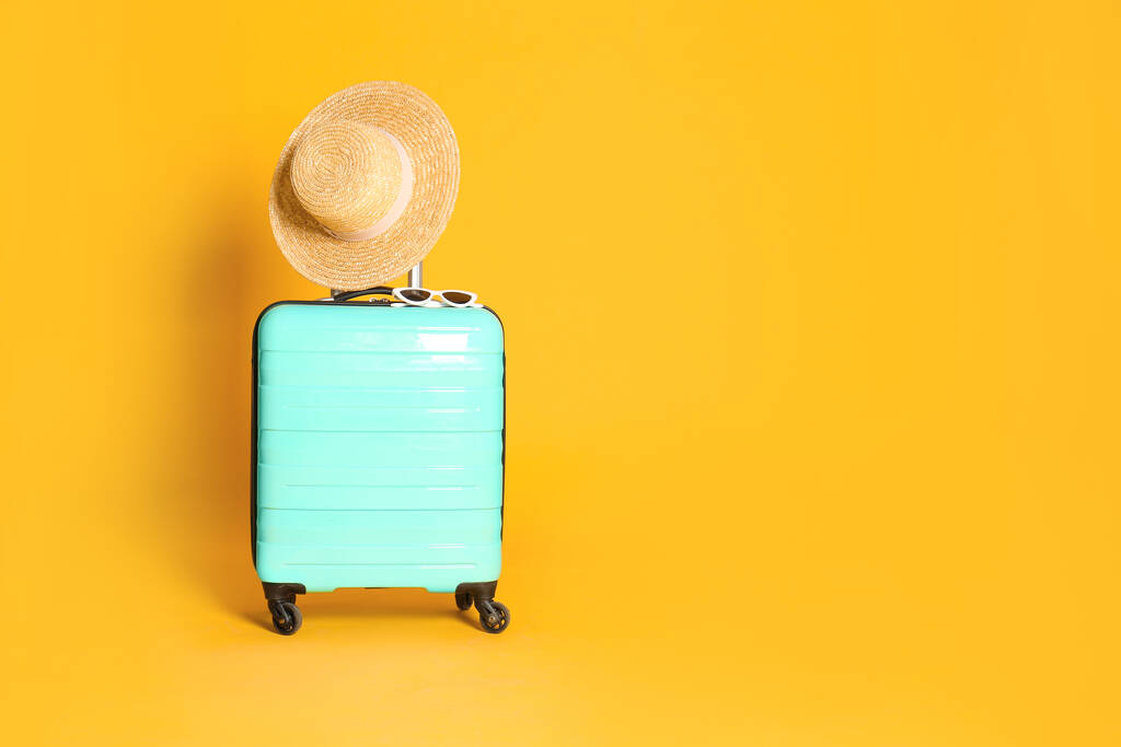 Sarı arka planda şapka ve güneş gözlükleriyle seyahat çantası, mesaj için yer. Yaz tatili - Fotoğraf, Görsel
