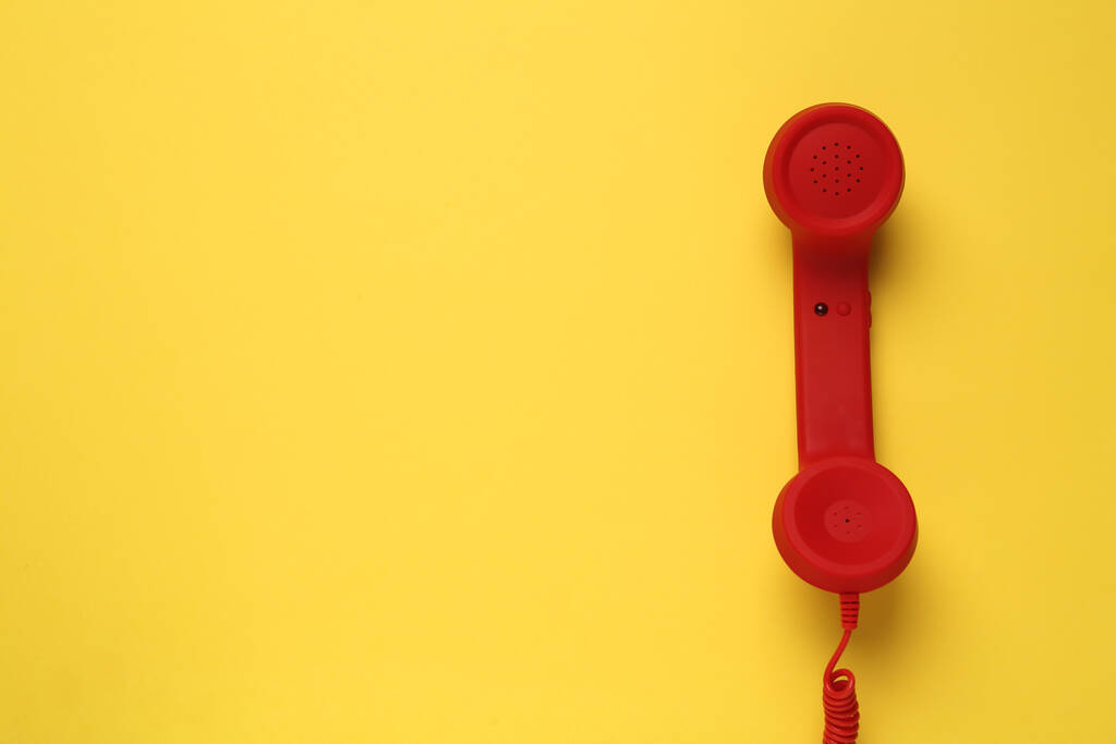 Roter Telefonhörer auf gelbem Hintergrund, Draufsicht. Hotline-Konzept - Foto, Bild