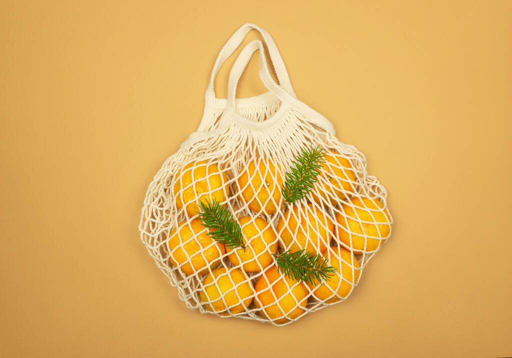 Una bolsa de malla blanca llena de mandarinas  - Foto, imagen