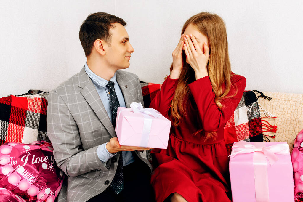 Романтическое свидание. Элегантный мужчина закрывает глаза на женщину, дарящую валентинку дома - Фото, изображение