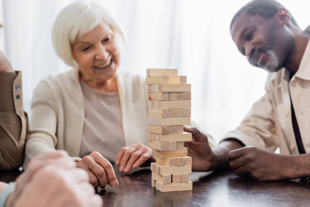 torony fatömbök az asztalon boldog multikulturális nyugdíjasok közelében homályos háttérrel - Fotó, kép