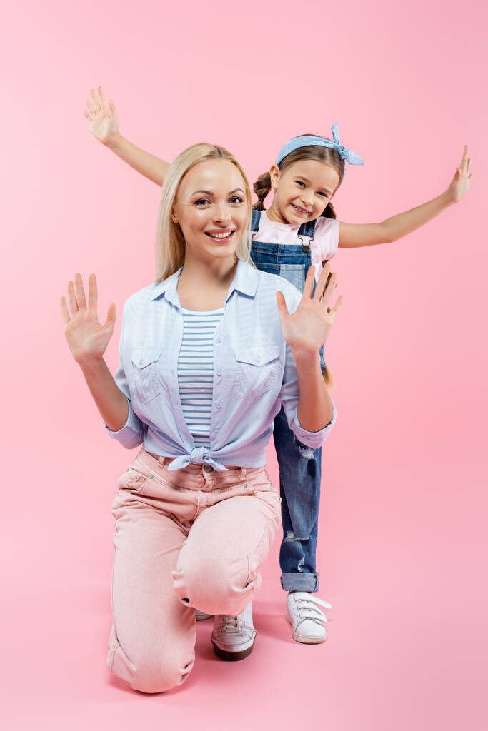 happy kid with outstretched hands standing behind mother on pink - Photo, Image