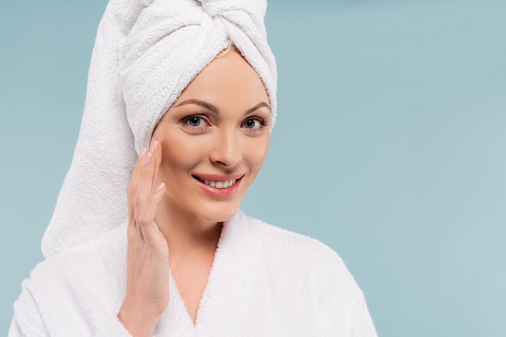 boldog nő fürdőköpenyben alkalmazása kozmetikai krém elszigetelt kék - Fotó, kép