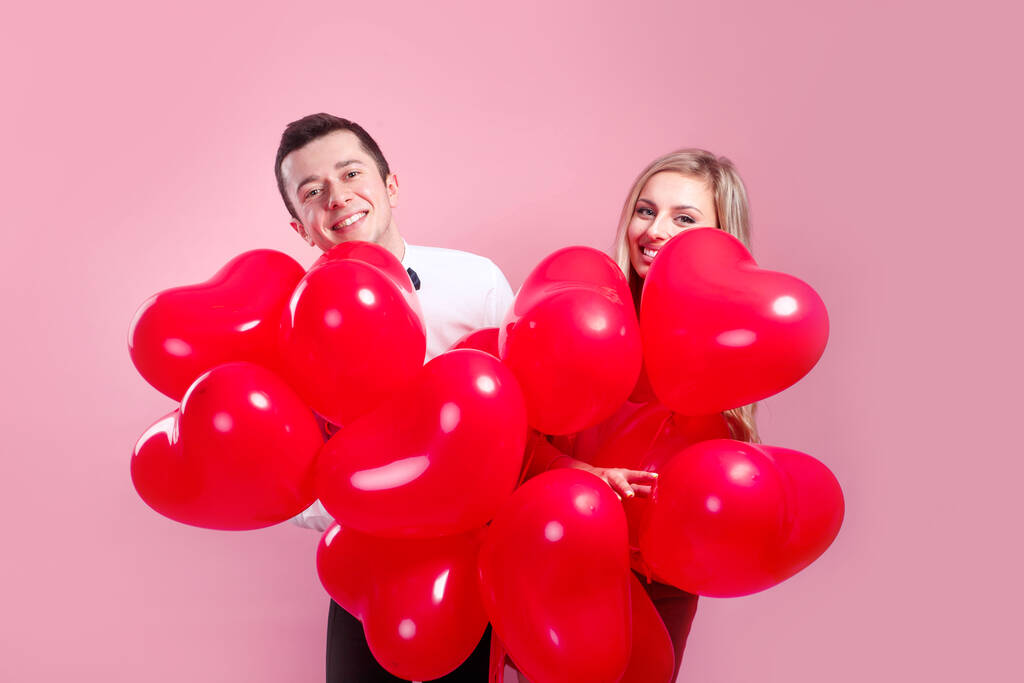 Saint Valentin. Surpris jeune couple avec des ballons coeur sur fond rose - Photo, image