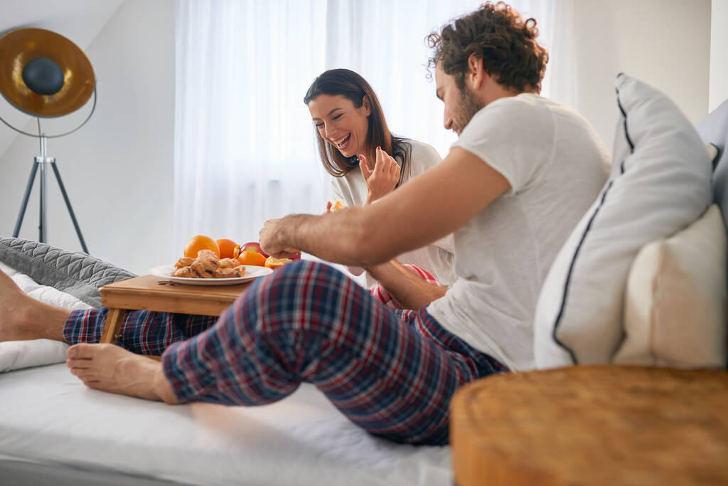 Um jovem casal que gosta de tomar um café da manhã na cama em seu quarto juntos. Amor, relacionamento, juntos - Foto, Imagem