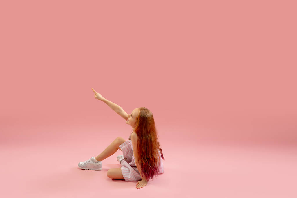 Childhood and dream about big and famous future. Pretty longhair girl isolated on coral pink background - Photo, Image