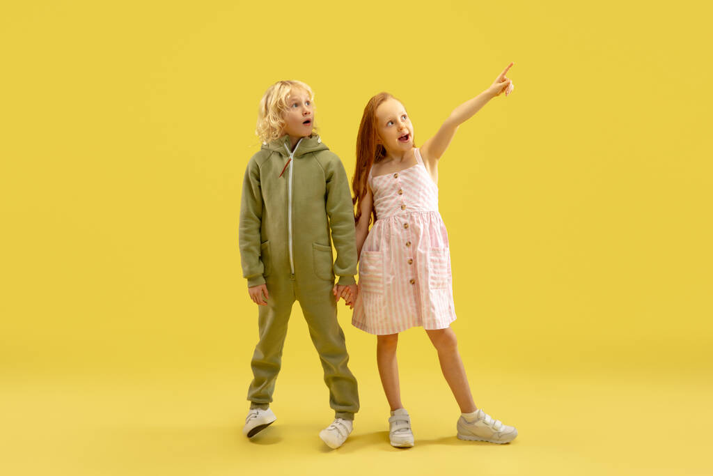 Kindheit und Traum von einer großen und berühmten Zukunft. Junge und Mädchen isoliert auf gelbem Studiohintergrund - Foto, Bild