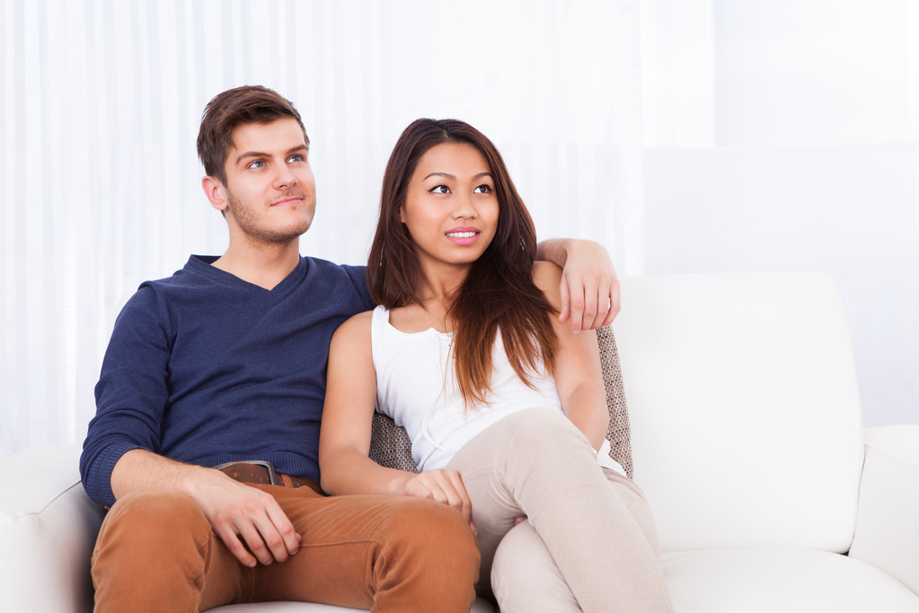 Sorridente giovane coppia seduta sul divano
 - Foto, immagini
