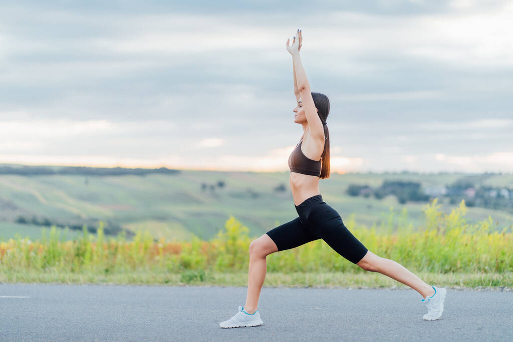 Yoga! Tegen de achtergrond van zonsopgang, sport meisje strekt zich uit. Kalmte en balans, een gezonde levensstijl. - Foto, afbeelding