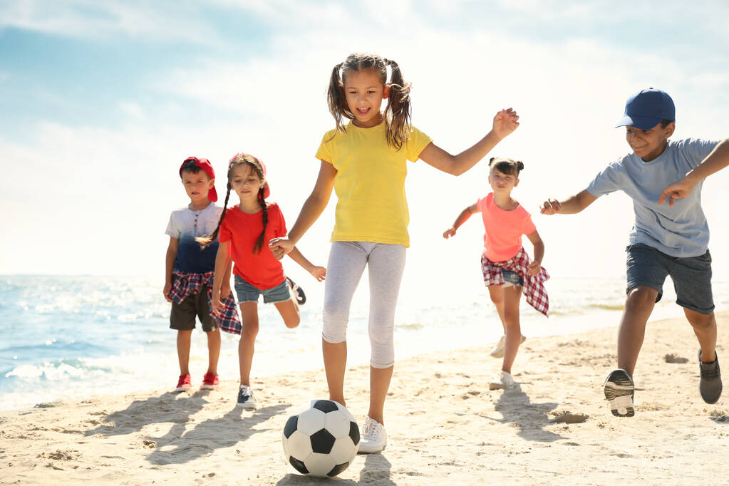 Aranyos gyerekek fociznak a parton a napsütéses napon. Nyári tábor - Fotó, kép