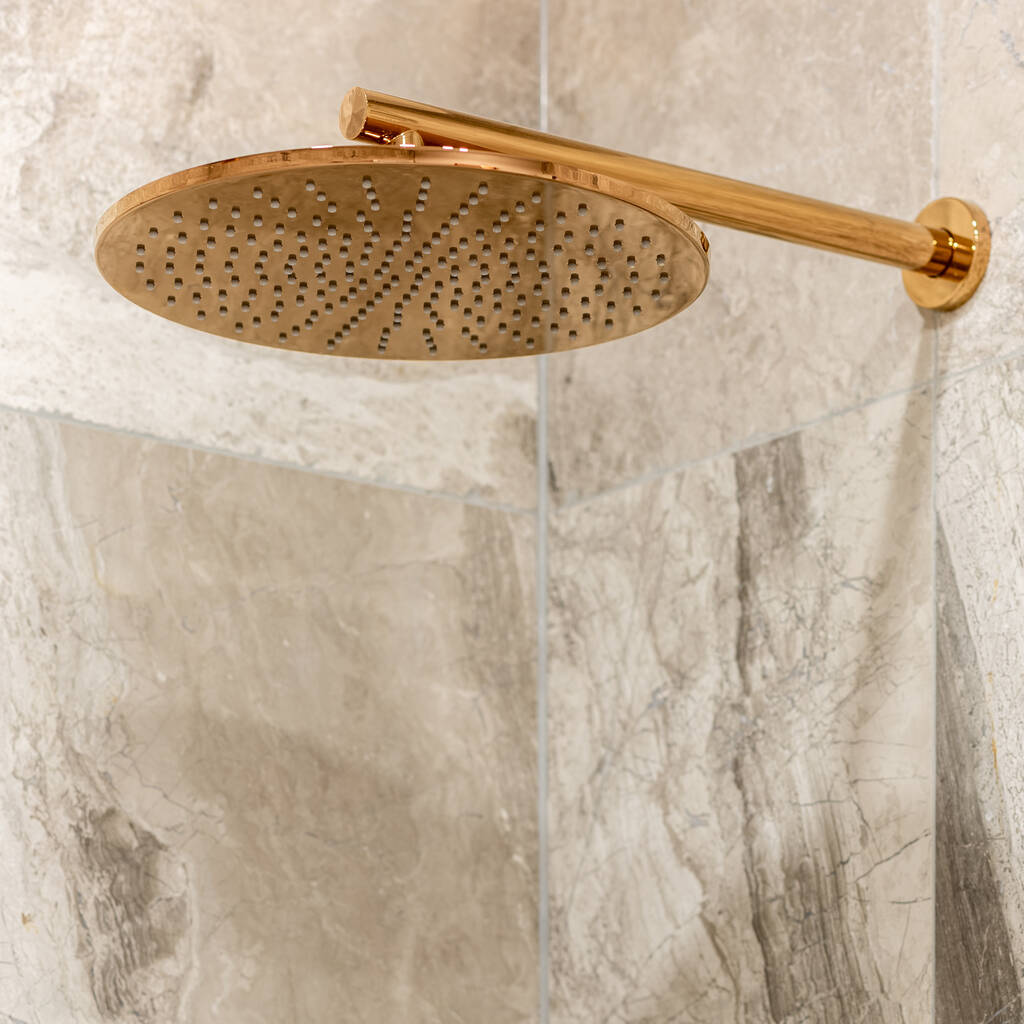 Primo piano su elegante soffione doccia in rame montato a parete con eleganti piastrelle in marmo beige - Foto, immagini
