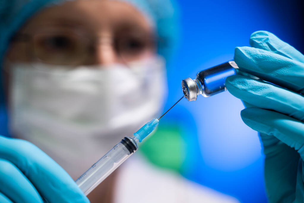Operaia medica in procinto di riempire una siringa con un medicinale - Foto, immagini