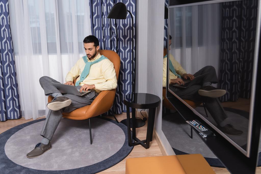 Libero professionista musulmano che utilizza il computer portatile in una moderna camera d'albergo  - Foto, immagini
