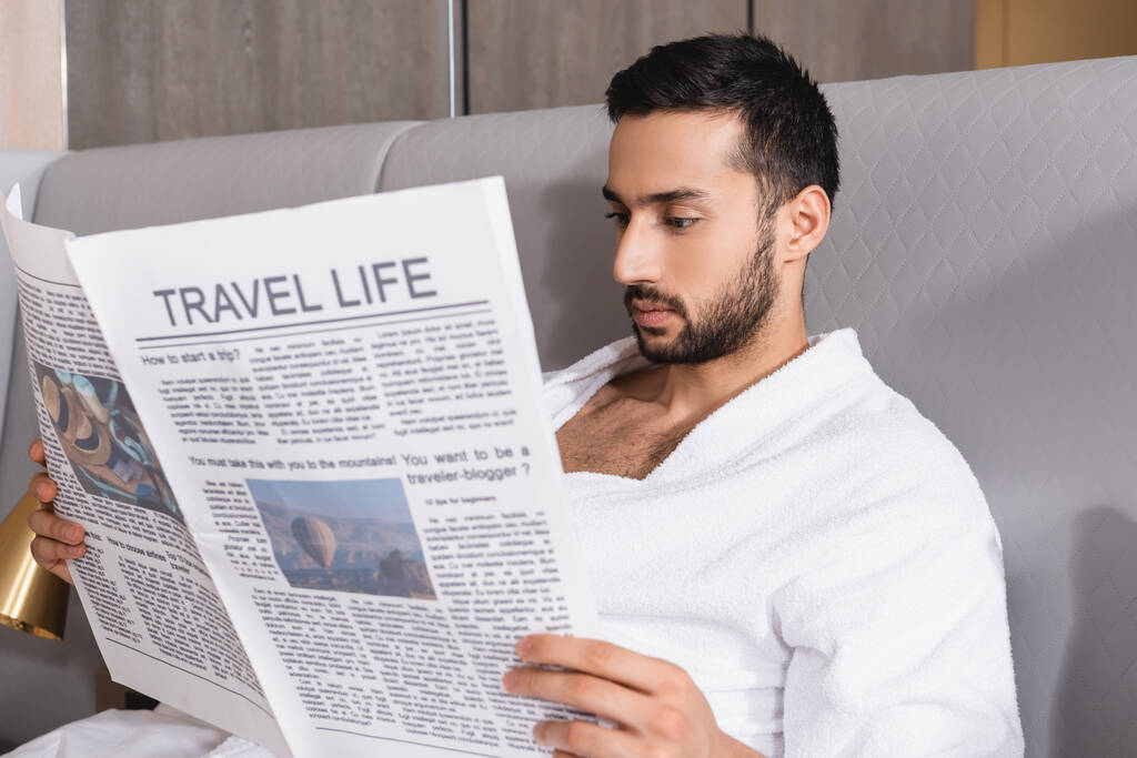 Arabian man reading newspaper with travel life on blurred foreground in hotel  - Photo, Image
