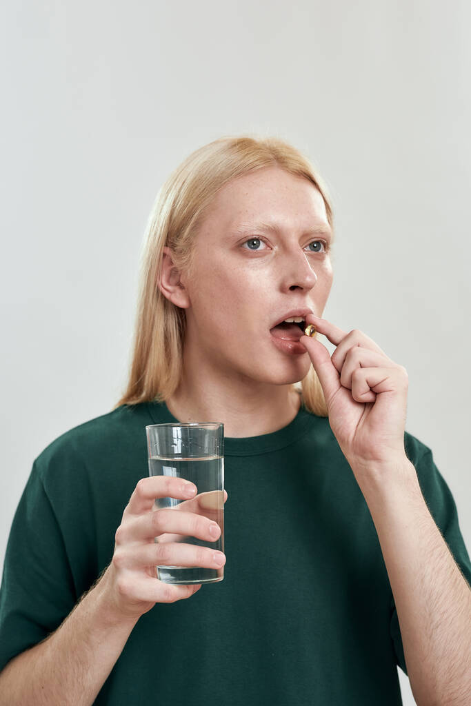 Portrait of young caucasian man swallowing vitamin - Photo, Image