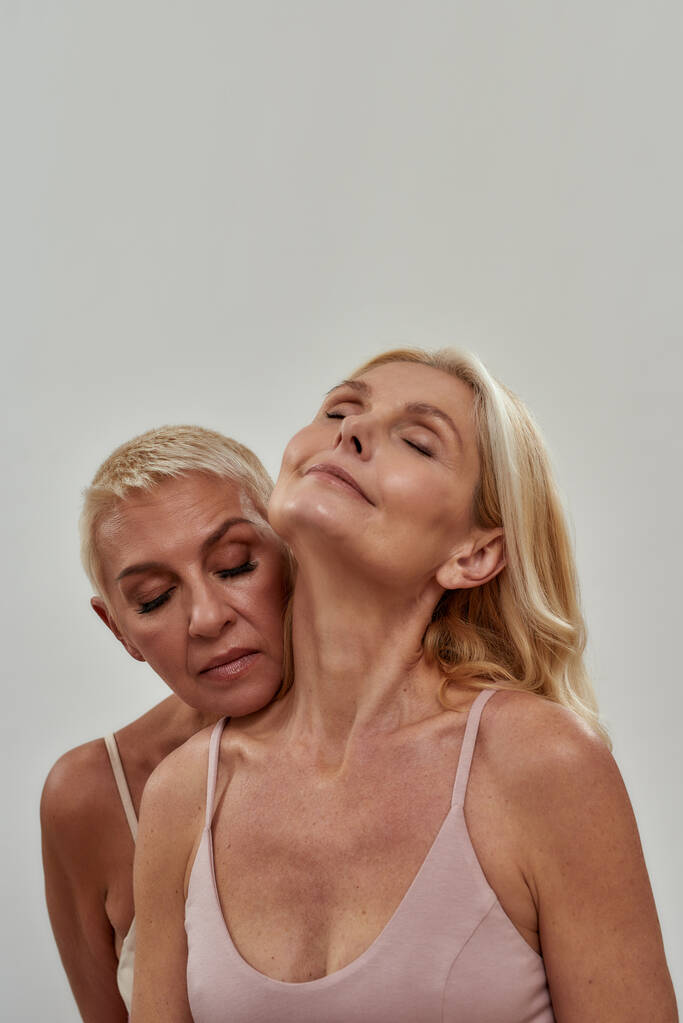 Studio muotokuva kaksi aistillinen blondi naiset seisovat yhdessä, poseeraa eristetty yli harmaa tausta - Valokuva, kuva