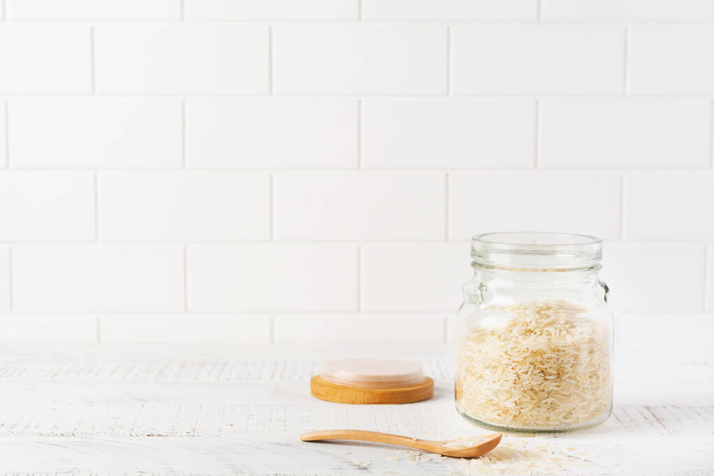 Syrová bílá odrůda rýže Arborio pro italské rizoto pokrmy ve skleněné nádobě na bílém betonu nebo na kamenném pozadí. Selektivní soustředění. Kopírovat prostor. - Fotografie, Obrázek