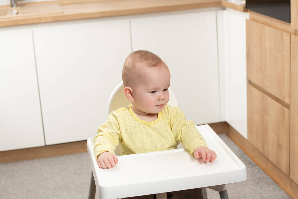 Bambino bambino seduto su una sedia e pronto a mangiare e alla ricerca di mamma - Foto, immagini