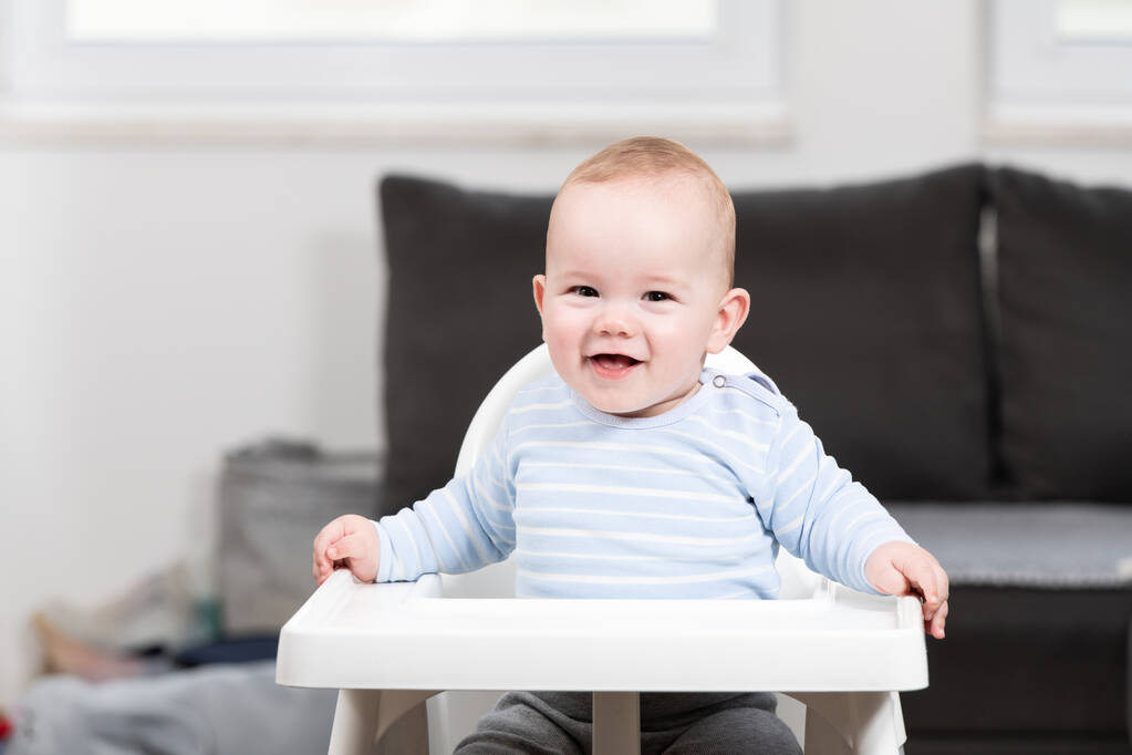 Portrait d'un bébé joyeux assis sur une chaise haute - Photo, image