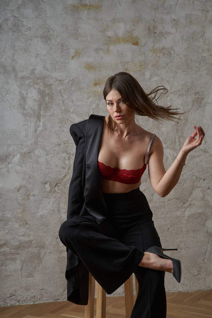 Krása mladá brunetka na sobě černé ležérní oblek a červená podprsenka pózování v apartmánech interiér - Fotografie, Obrázek