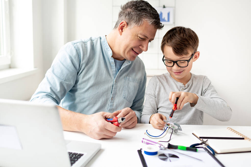 Father and son repairing an electrical outlet while sitting at a desk. Learn for life concept - Photo, Image