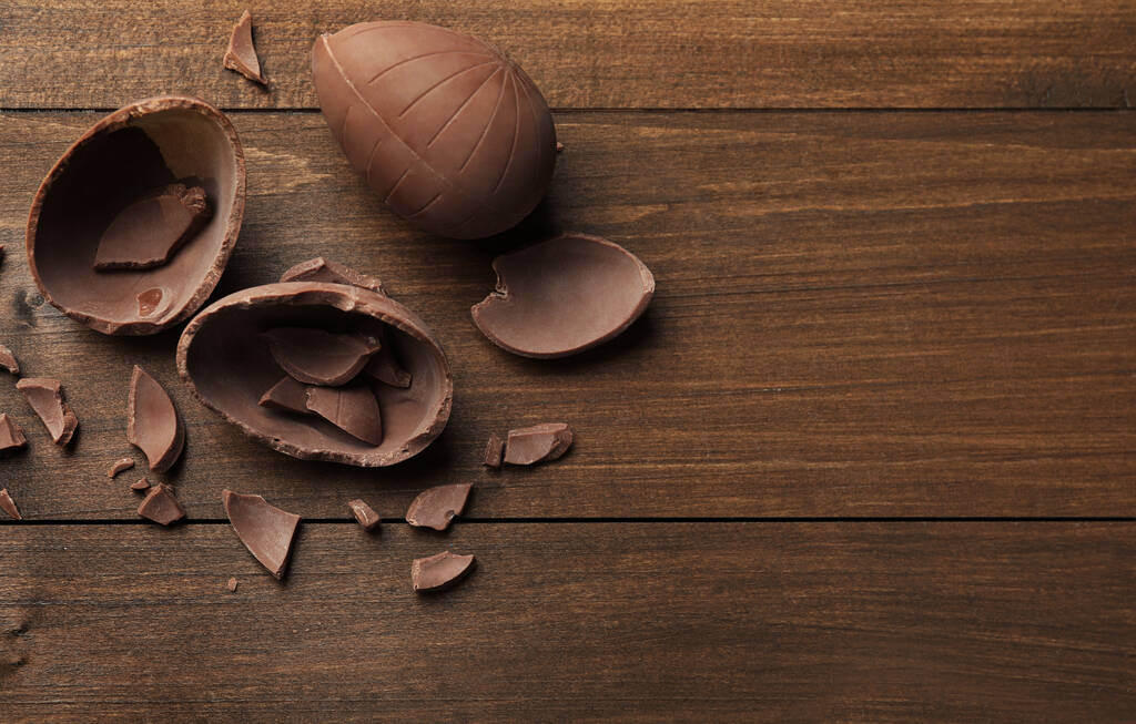Rikkinäiset suklaamunat puupöydällä, tasainen. Tekstitila - Valokuva, kuva