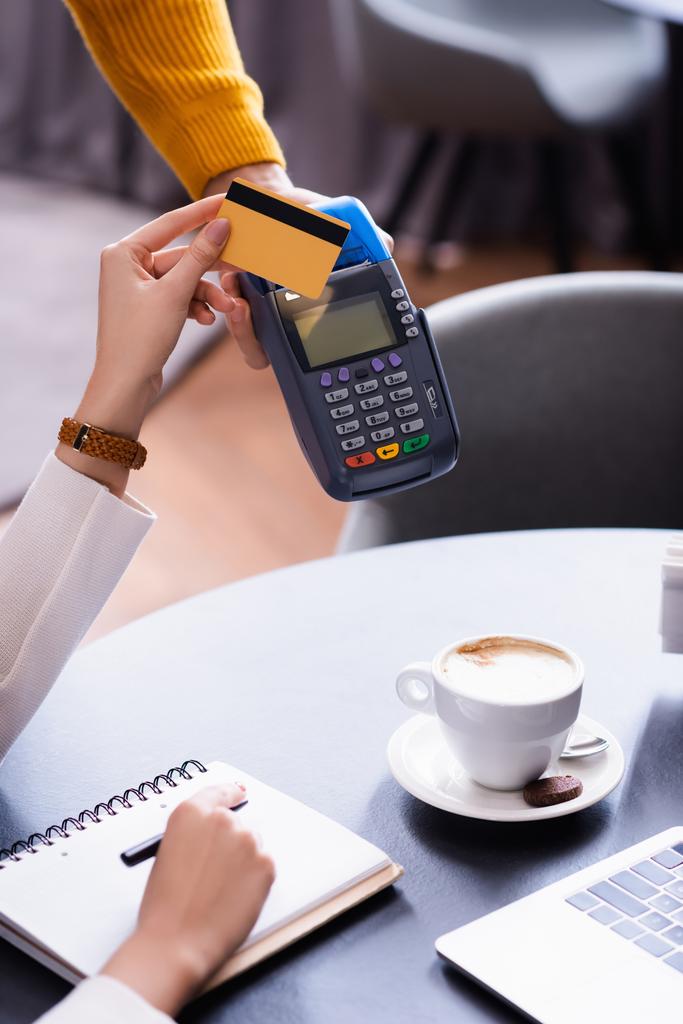 cropped view of freelancer holding credit card near payment terminal un hand of waiter - Photo, Image