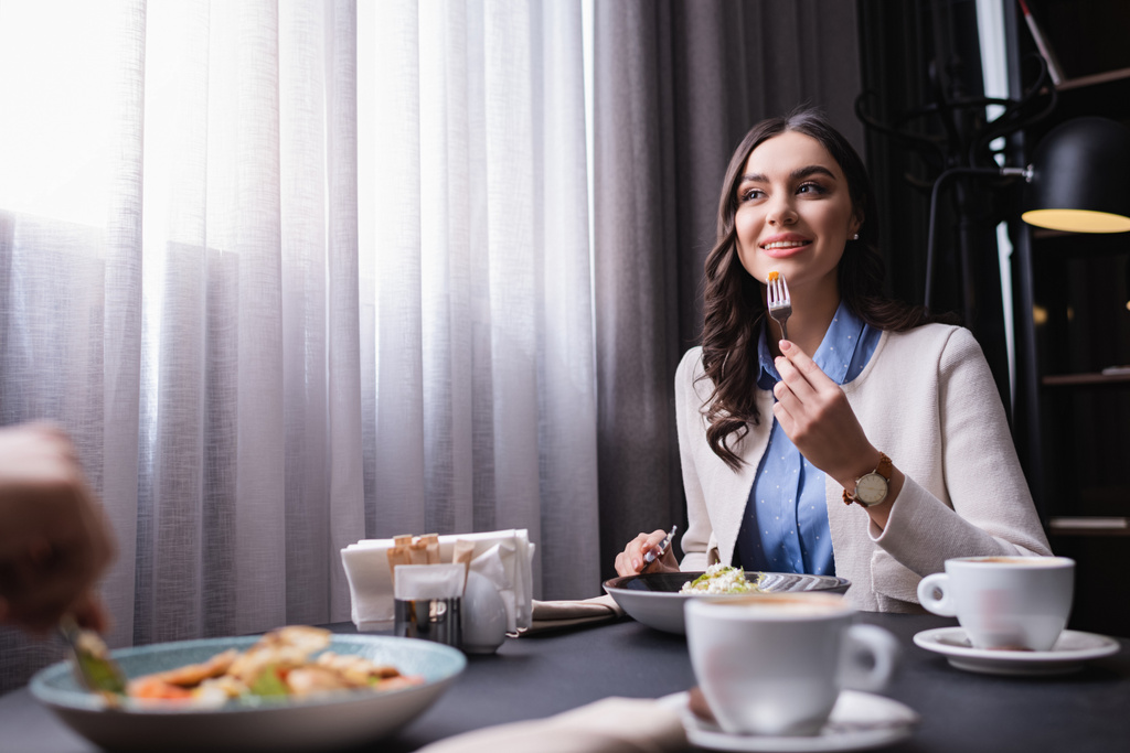 Smiling woman dinning with boyfriend on blurred foreground in restaurant  - Photo, Image