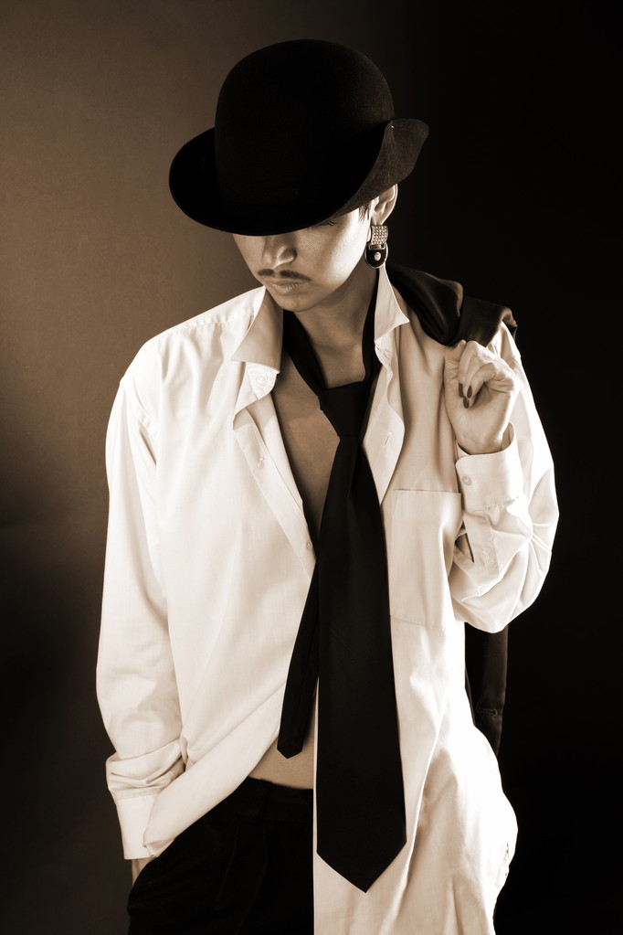 Молода модель моди в капелюсі, велика чоловіча сорочка і пальто проти чорного
 - Фото, зображення