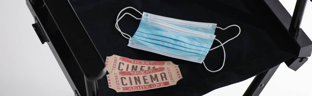 cinema tickets and medical masks on black filmmaker chair on white, banner - Photo, Image