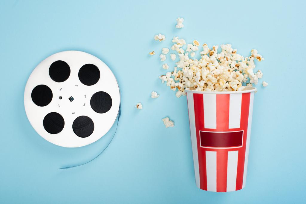 shora pohled na film cívku u kbelíku popcornu na modré, koncepce kina - Fotografie, Obrázek