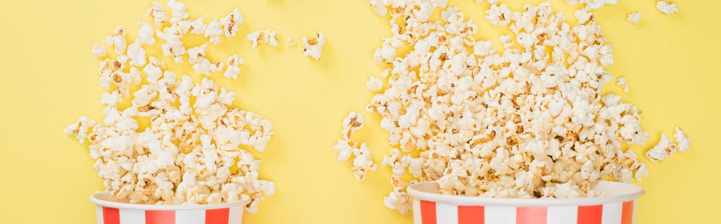 vista dall'alto di grandi e piccoli secchi con popcorn croccanti su giallo, banner, concetto di cinema  - Foto, immagini